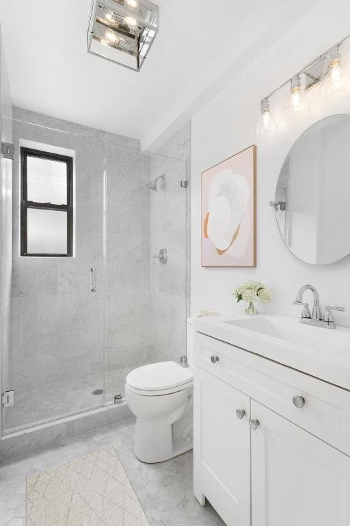 full bath with a stall shower, marble finish floor, vanity, and toilet