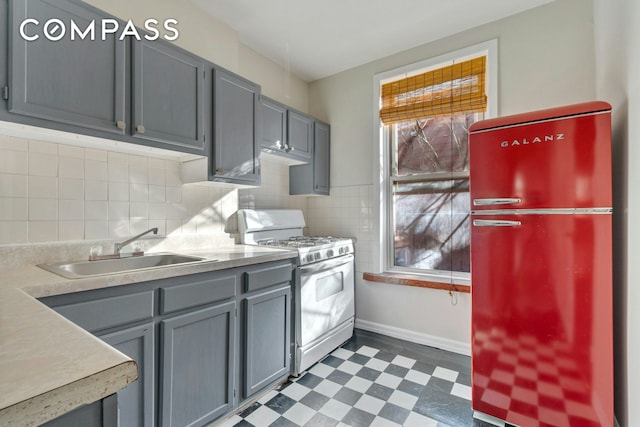 kitchen with range with gas cooktop, dark floors, freestanding refrigerator, gray cabinetry, and a sink