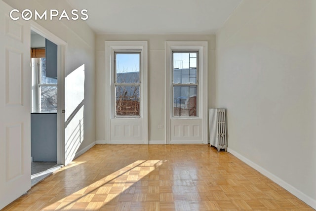 unfurnished room featuring baseboards and radiator