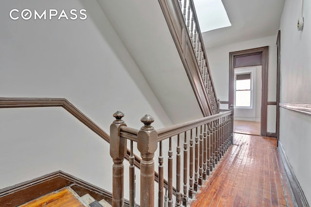 stairway with wood-type flooring and a skylight