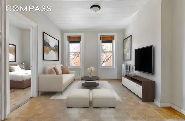 living room featuring baseboards, crown molding, and radiator heating unit