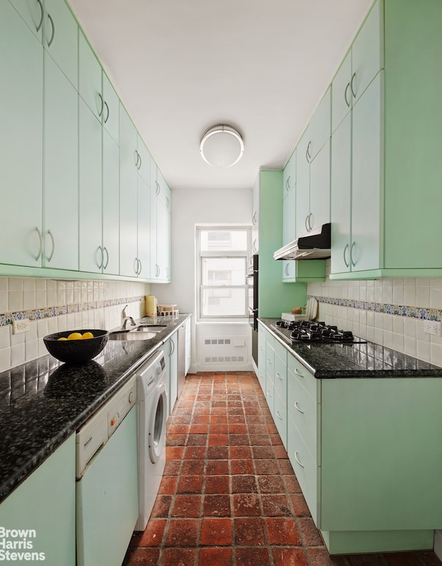 kitchen with a sink, brick floor, washer / clothes dryer, stainless steel appliances, and under cabinet range hood