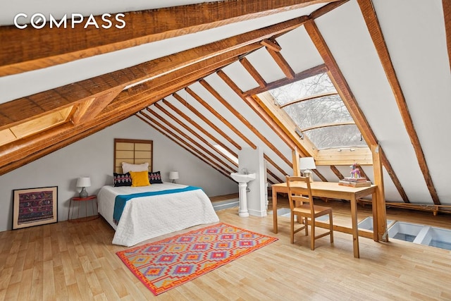 bedroom featuring vaulted ceiling with skylight and wood finished floors