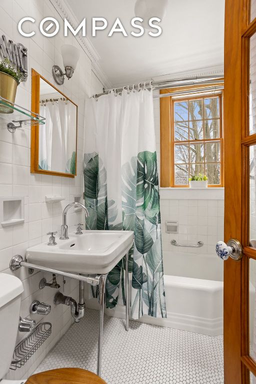 full bath featuring toilet, tile walls, tile patterned floors, tasteful backsplash, and shower / bathtub combination with curtain