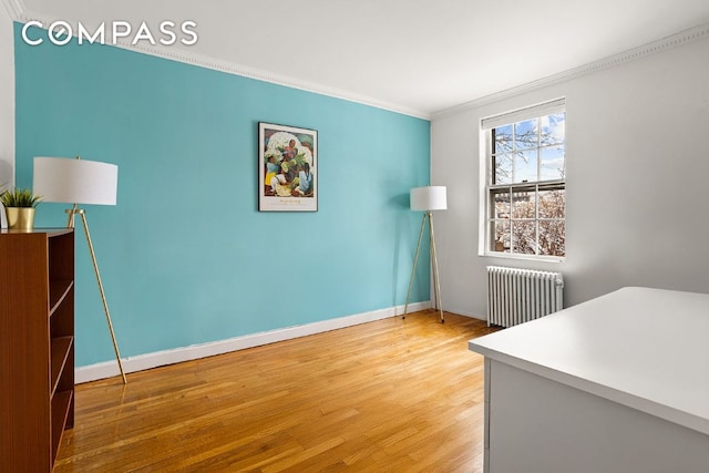 office featuring baseboards, radiator heating unit, wood finished floors, and crown molding