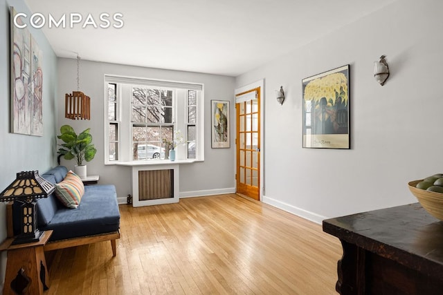 living area featuring light wood-style floors, radiator heating unit, and baseboards