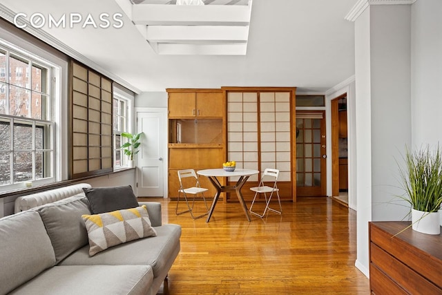 living room featuring ornamental molding, a skylight, baseboards, and wood finished floors