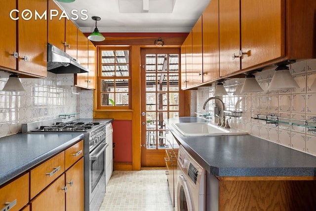 kitchen with brown cabinets, washer / clothes dryer, stainless steel range with gas stovetop, a sink, and under cabinet range hood