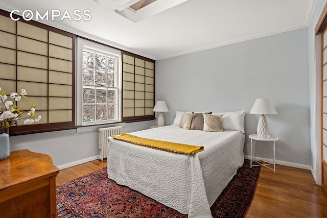 bedroom with radiator, crown molding, baseboards, and wood finished floors