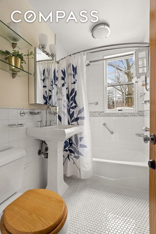 bathroom featuring shower / tub combo, tile walls, toilet, and tile patterned floors