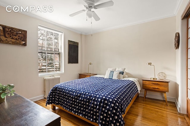 bedroom featuring wood finished floors, a ceiling fan, baseboards, radiator, and crown molding