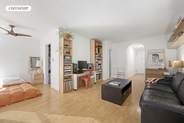 living area with visible vents, arched walkways, ceiling fan, light wood-style flooring, and ornamental molding