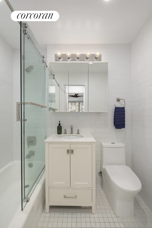 full bathroom featuring enclosed tub / shower combo, tile walls, toilet, and vanity