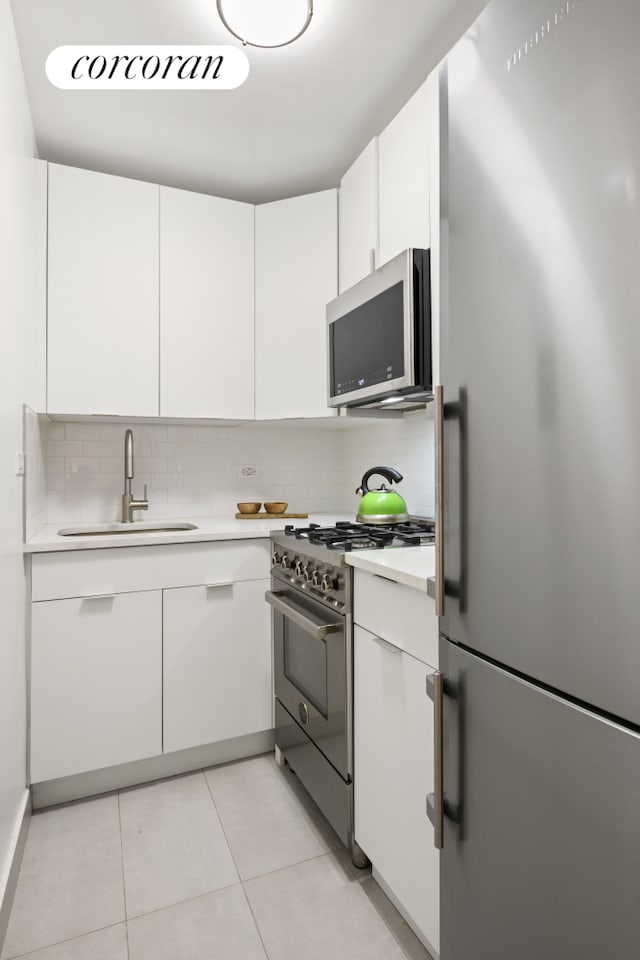 kitchen with white cabinetry, appliances with stainless steel finishes, light countertops, and a sink