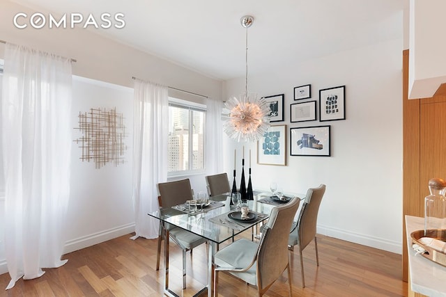 dining area featuring an inviting chandelier, light wood-style flooring, and baseboards