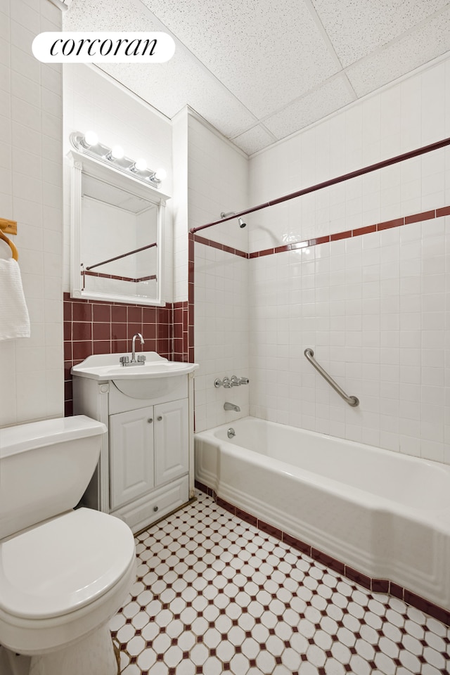 full bath with tile walls, shower / bathtub combination, toilet, vanity, and tile patterned floors