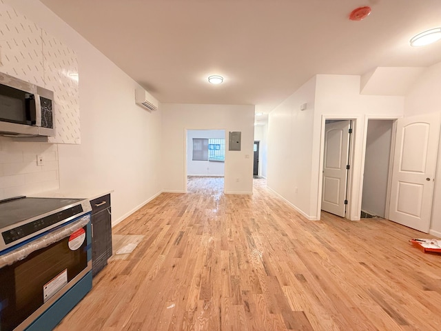 kitchen featuring a wall mounted AC, electric panel, backsplash, appliances with stainless steel finishes, and light wood finished floors