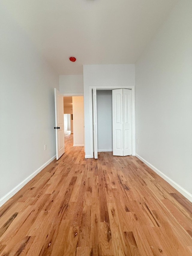 unfurnished bedroom with a closet, baseboards, and light wood finished floors