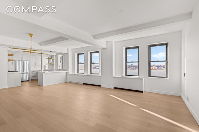 bedroom featuring wood finished floors, baseboards, two closets, and beamed ceiling