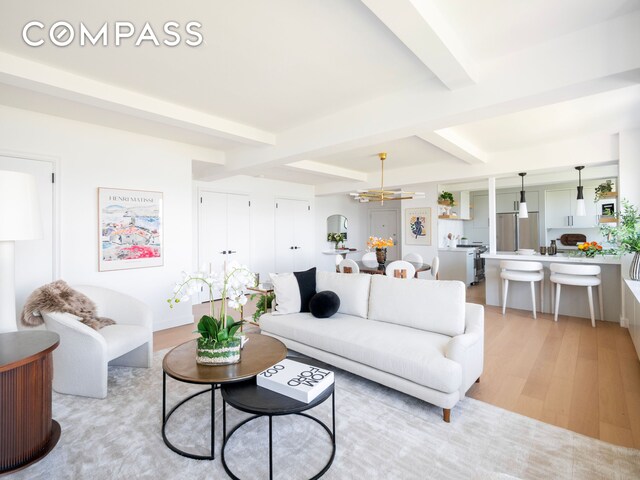 living area featuring light wood-style floors, an inviting chandelier, and beamed ceiling