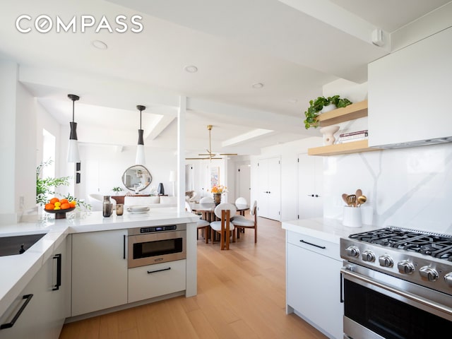 kitchen with appliances with stainless steel finishes, pendant lighting, modern cabinets, and light wood-type flooring