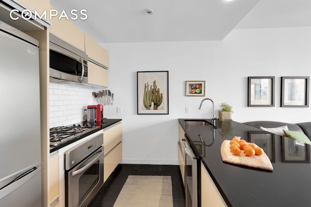 kitchen featuring a sink, baseboards, appliances with stainless steel finishes, decorative backsplash, and dark countertops