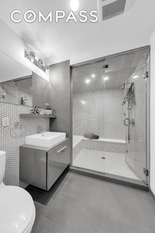 full bathroom featuring vanity, tile patterned flooring, a shower stall, and toilet