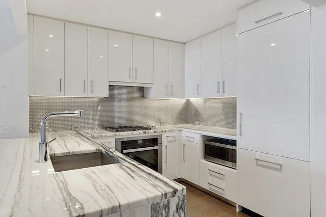 kitchen with stainless steel appliances, white cabinets, a sink, and modern cabinets