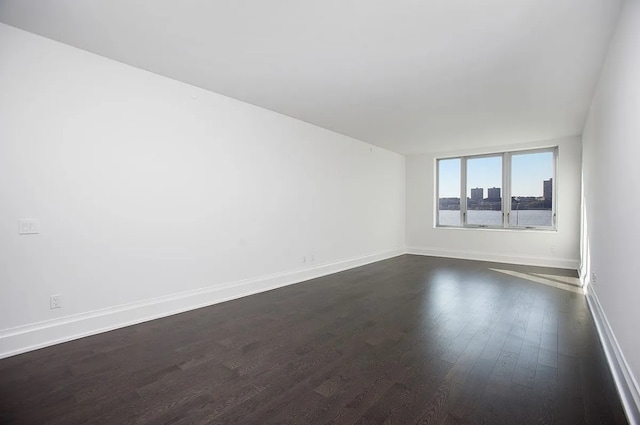 spare room featuring dark wood-style flooring and baseboards