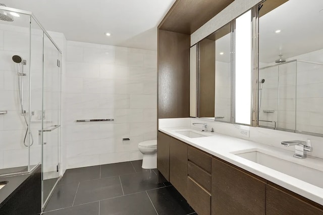 full bath featuring tile patterned floors, a sink, tile walls, and a shower stall