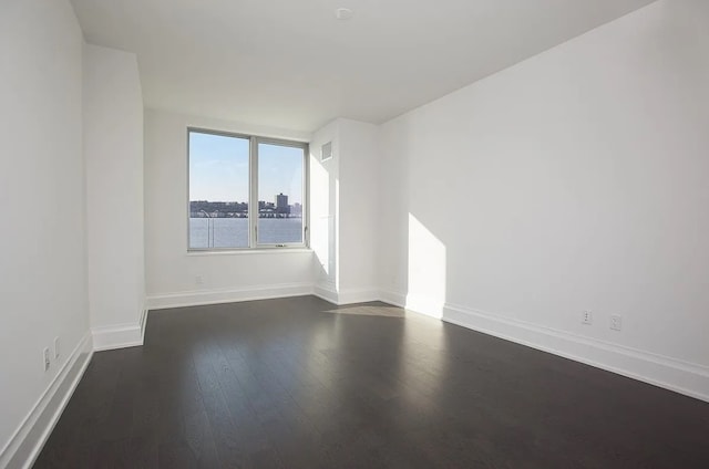 unfurnished room featuring baseboards and dark wood-style flooring