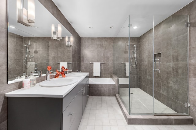 bathroom featuring double vanity, a shower stall, tile walls, and a sink