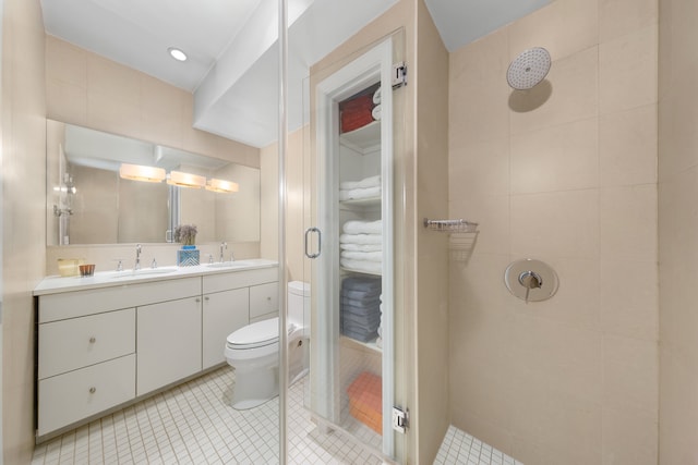 bathroom featuring double vanity, a sink, toilet, and a shower stall