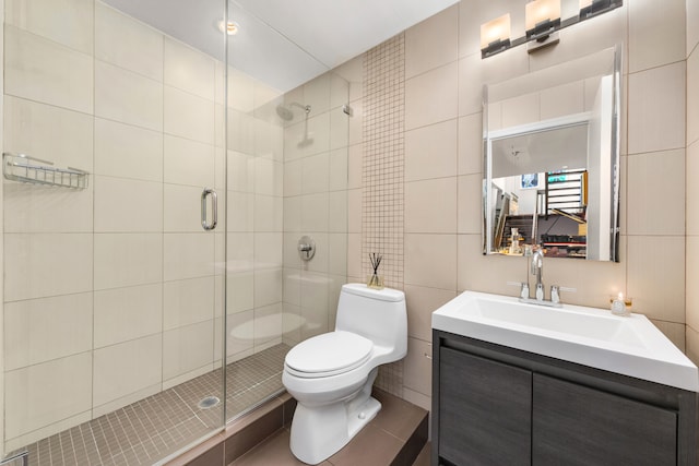 bathroom featuring a shower stall, vanity, toilet, and tile walls