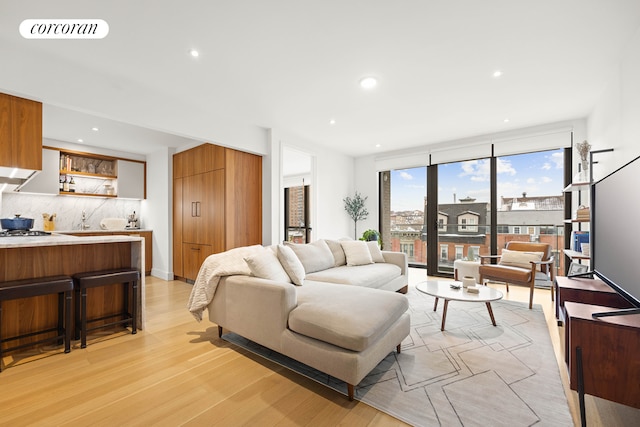 living area with light wood finished floors, visible vents, and recessed lighting