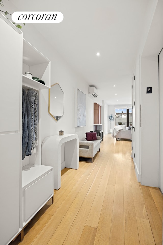 hallway featuring recessed lighting, an AC wall unit, and hardwood / wood-style floors