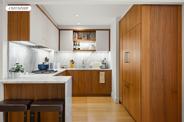 kitchen with brown cabinetry, modern cabinets, a breakfast bar, and tasteful backsplash