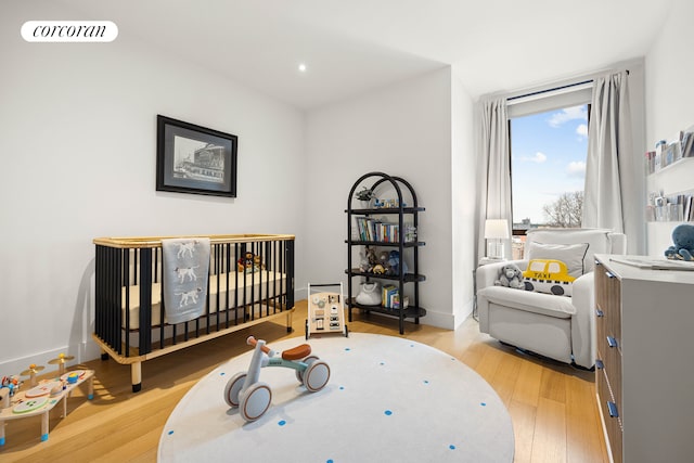 bedroom featuring a crib, baseboards, visible vents, light wood-style floors, and recessed lighting