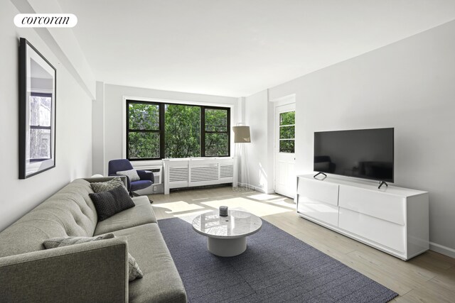 living area featuring visible vents, light wood-style flooring, and baseboards