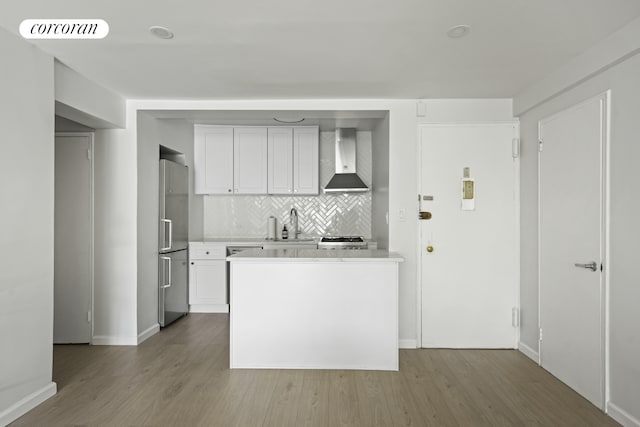 kitchen with light countertops, visible vents, wall chimney range hood, wood finished floors, and high end refrigerator