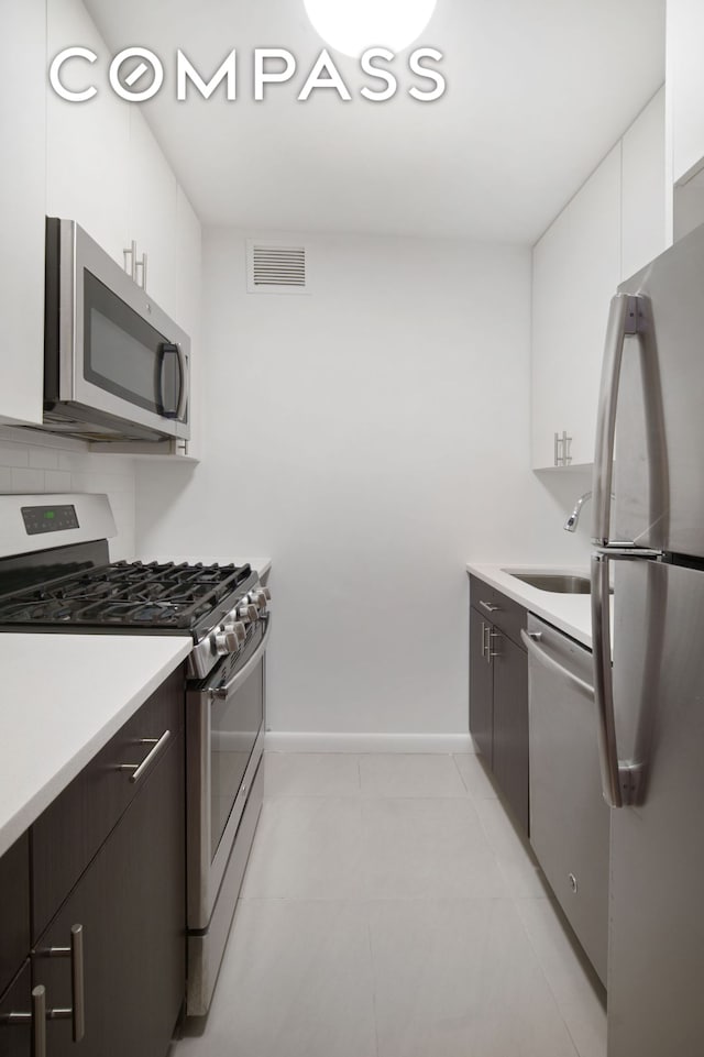 kitchen featuring appliances with stainless steel finishes, a sink, visible vents, and white cabinets