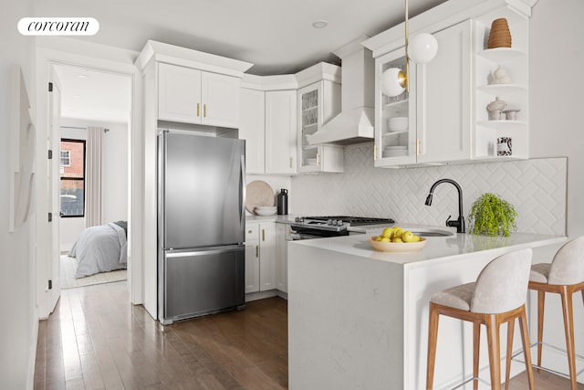 kitchen featuring a breakfast bar area, custom exhaust hood, visible vents, appliances with stainless steel finishes, and a peninsula