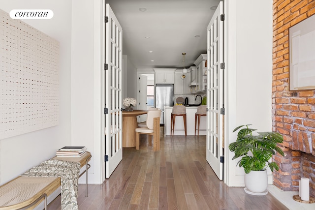 hallway featuring dark wood-type flooring, recessed lighting, and a sink