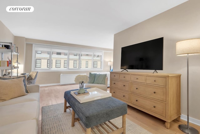 living area featuring light wood-style flooring, radiator heating unit, visible vents, and baseboards