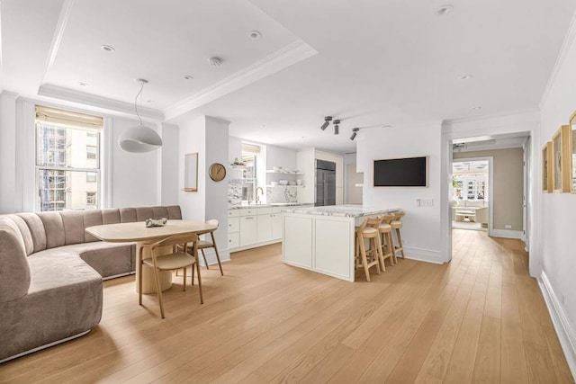 kitchen featuring built in fridge, white cabinets, crown molding, and open floor plan