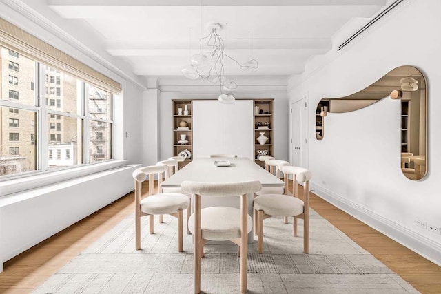 dining room featuring baseboards, wood finished floors, beam ceiling, and an inviting chandelier