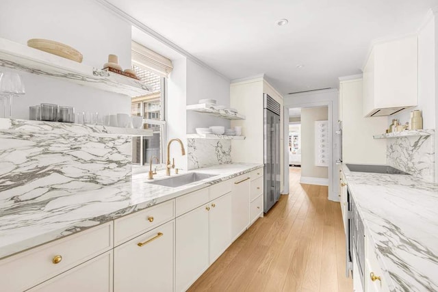 kitchen featuring light stone counters, white cabinets, a sink, and open shelves