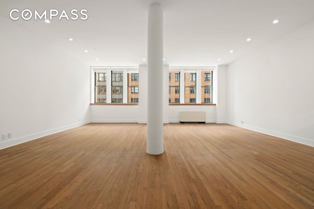 unfurnished living room with baseboards, wood finished floors, and recessed lighting