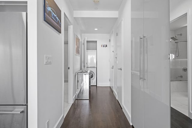 corridor featuring recessed lighting, baseboards, dark wood finished floors, and stacked washer / drying machine