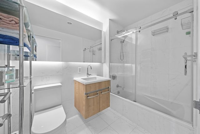 bathroom with marble finish floor, shower / bath combination with glass door, vanity, and toilet